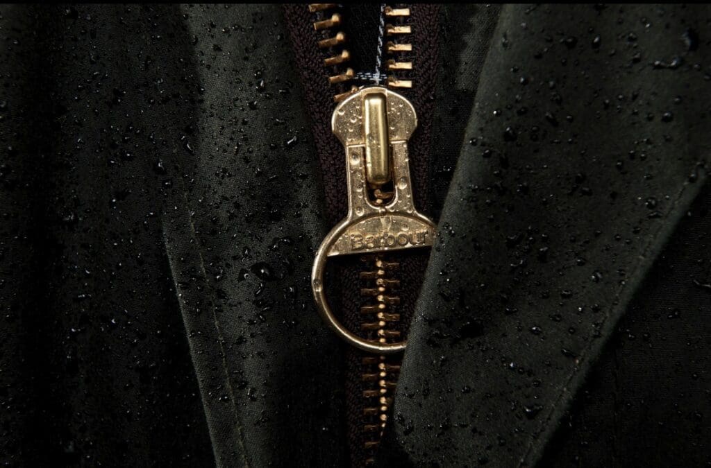 Brass Barbour zip on a waxed jacket with raindrops