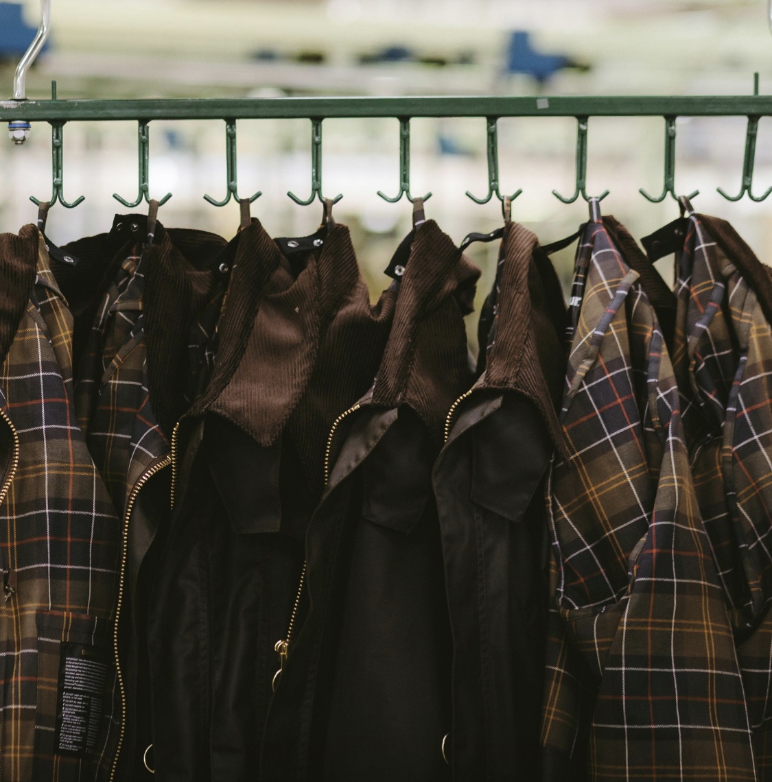 Barbour wax jackets with tartan linings hanging on hooks